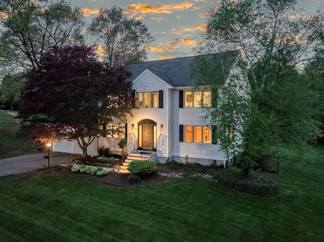 view of front facade featuring a chimney, a front lawn, and driveway