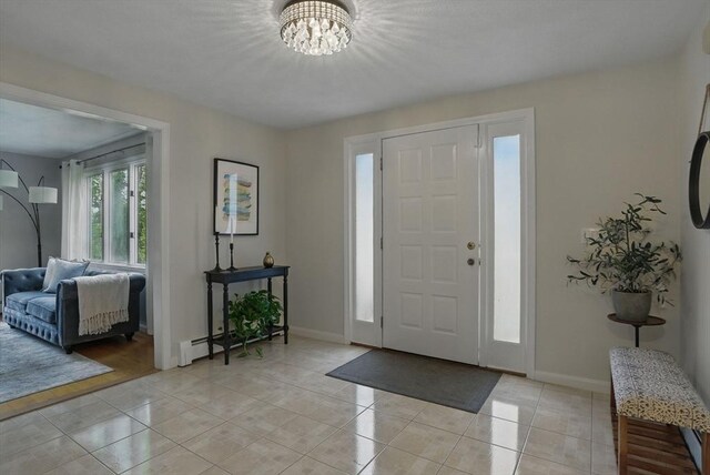 entrance foyer featuring a chandelier, light tile patterned floors, and baseboards