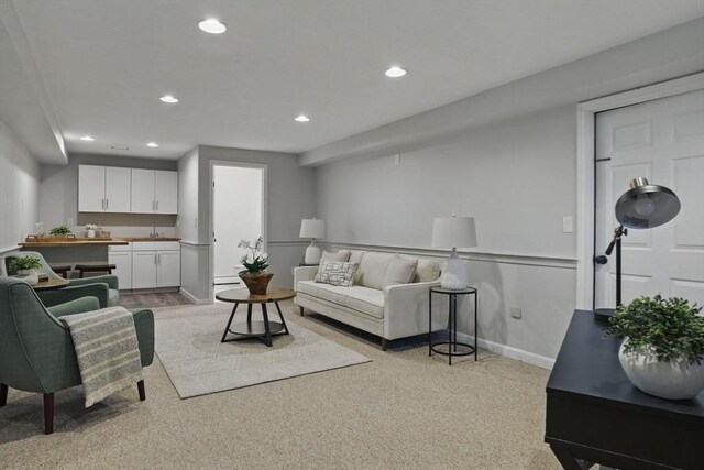 living room with recessed lighting, baseboards, bar, and light carpet