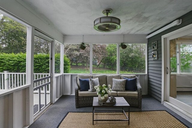 sunroom featuring baseboard heating, an outdoor hangout area, and healthy amount of natural light