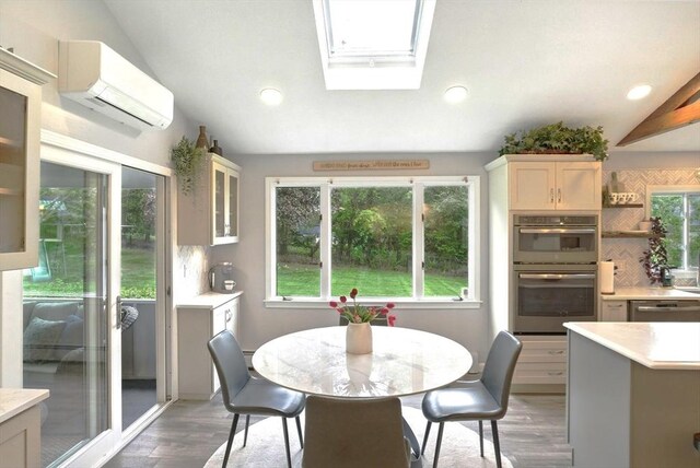 dining room with a wall mounted AC, wood finished floors, a skylight, recessed lighting, and vaulted ceiling