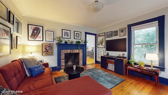 living room with ornamental molding, light wood-type flooring, and a brick fireplace