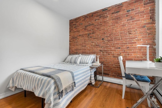 bedroom featuring brick wall, wood finished floors, and baseboards
