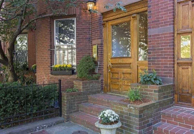 property entrance with brick siding and fence