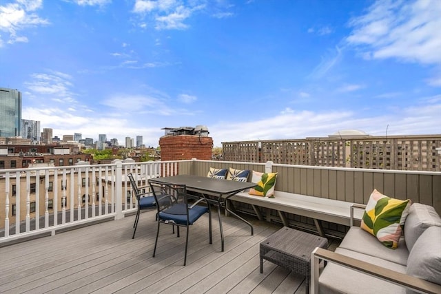 wooden deck featuring outdoor dining space and a skyline view