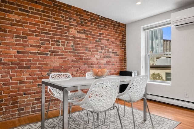 dining space featuring a wall unit AC, brick wall, wood finished floors, and a baseboard radiator