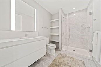 bathroom featuring vanity, toilet, and tiled shower