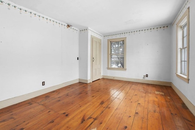 unfurnished room with a healthy amount of sunlight, baseboards, and hardwood / wood-style floors