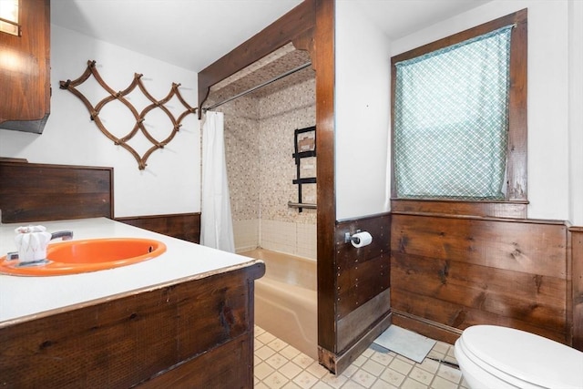 full bath featuring a wainscoted wall, shower / tub combo with curtain, vanity, and toilet