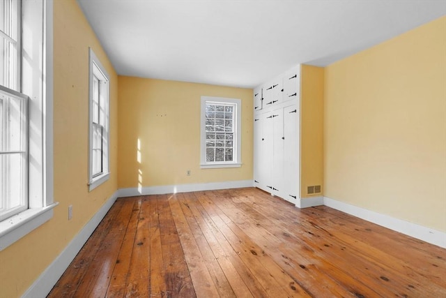 unfurnished room with wood-type flooring, a wealth of natural light, and baseboards