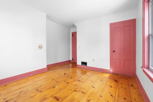 unfurnished room with visible vents, light wood-style flooring, and baseboards