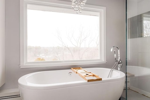 bathroom with a tub, a baseboard radiator, and a chandelier