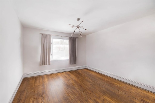 unfurnished room with wood-type flooring and an inviting chandelier