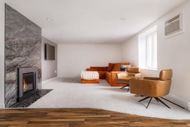 sitting room with a wall mounted air conditioner, a fireplace, and wood-type flooring