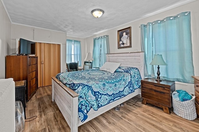 bedroom with a textured ceiling, ornamental molding, and wood finished floors