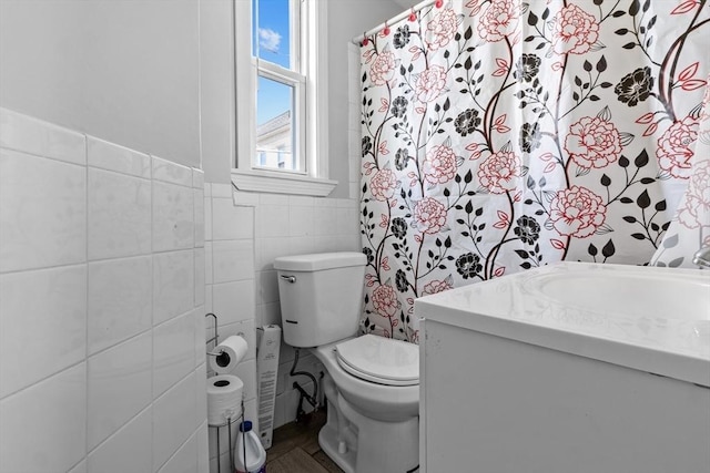 full bath featuring toilet, vanity, and tile walls