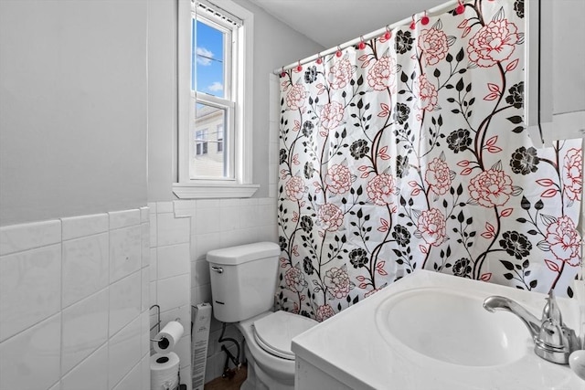 full bath with a wainscoted wall, tile walls, toilet, and vanity