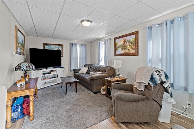 living area with a drop ceiling and wood finished floors