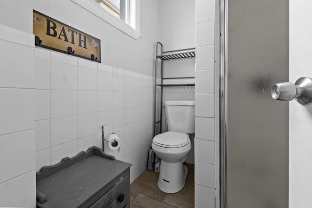 bathroom featuring toilet, a stall shower, and tile walls