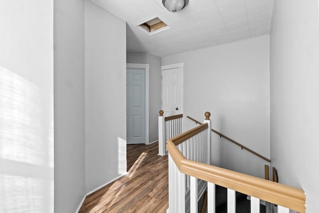 hallway with wood finished floors, an upstairs landing, and attic access