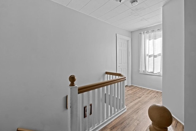 hall featuring an upstairs landing and wood finished floors