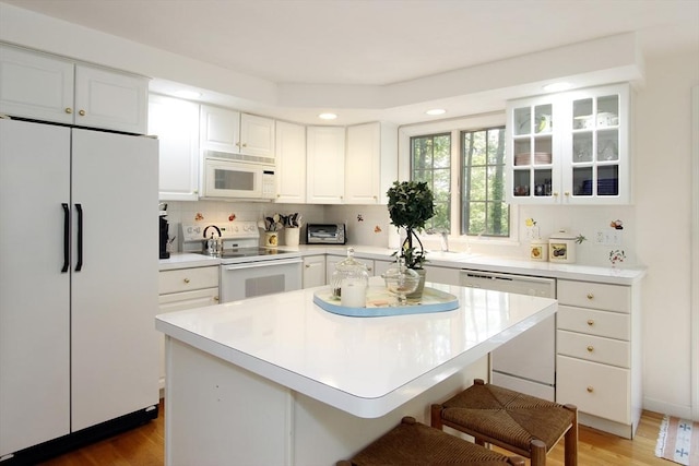 18 Periwinkle Ln, Mashpee, MA 02649 - kitchen featuring white appliances, white cabinets, a breakfast bar area, recessed lighting, and light countertops