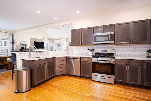 194 Crownshield Ave Unit 194, Uxbridge, MA 01569 - kitchen with stainless steel appliances, vaulted ceiling, light wood-style floors, a peninsula, and dark brown cabinetry