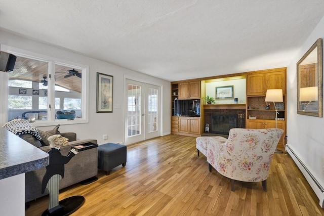 living area featuring a baseboard heating unit, a brick fireplace, light wood-style flooring, and french doors