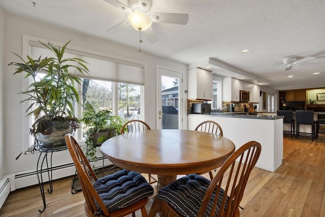 dining room with light wood-style flooring, a textured ceiling, and ceiling fan