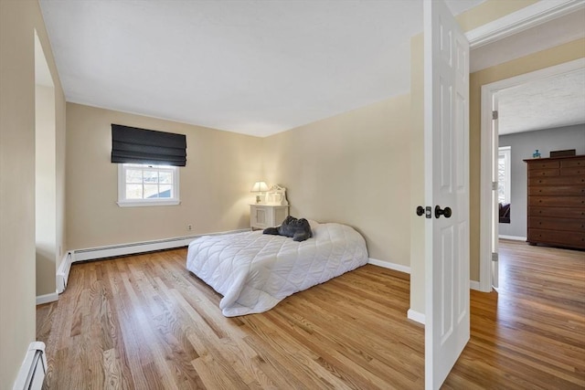 bedroom featuring a baseboard radiator, baseboards, baseboard heating, and wood finished floors