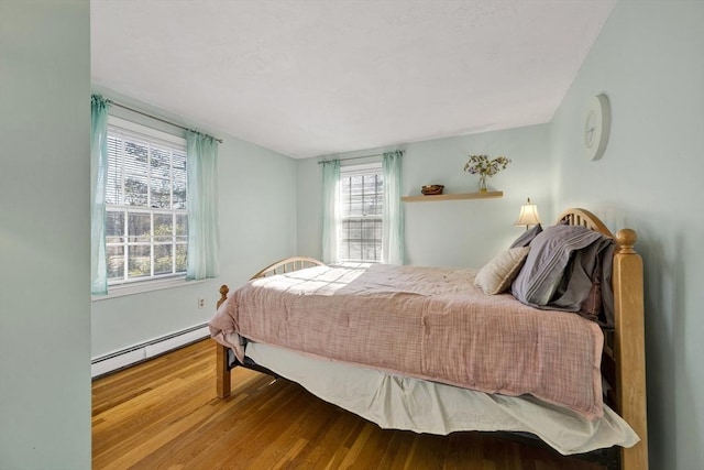 bedroom with wood finished floors and a baseboard radiator