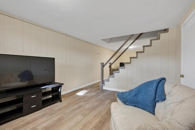 living area with stairway, baseboards, and light wood finished floors