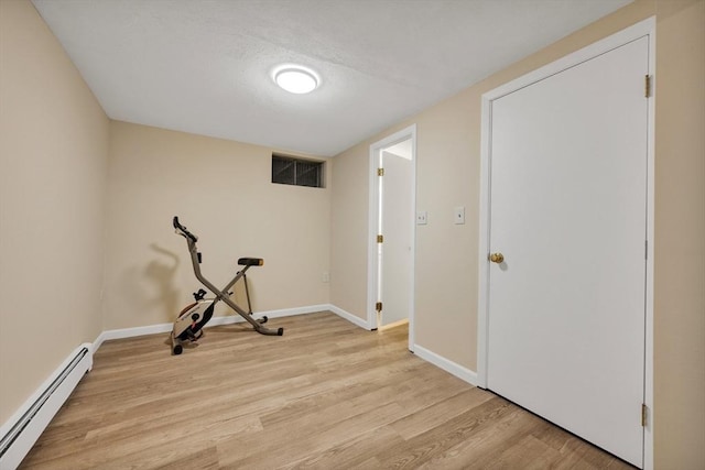 exercise room featuring light wood-style flooring, baseboards, visible vents, and a baseboard radiator