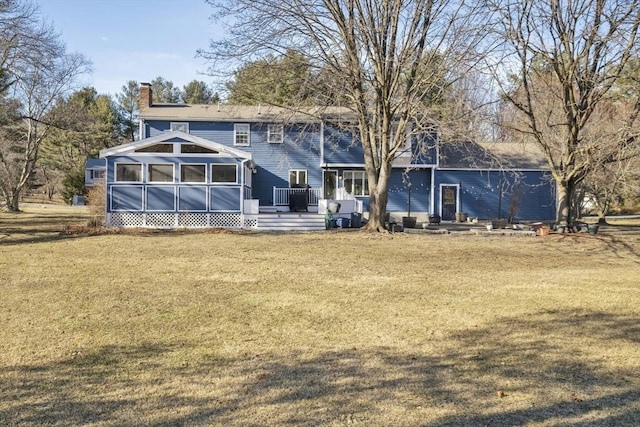 back of house with a lawn, a sunroom, and a chimney