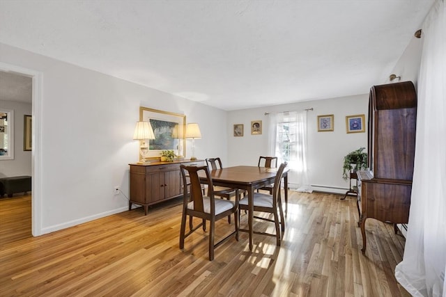 dining space with baseboards, light wood-style floors, and baseboard heating