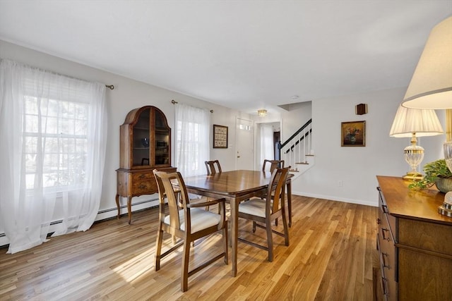 dining area with stairway, a healthy amount of sunlight, light wood-type flooring, and baseboards