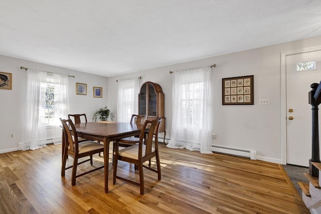 dining space featuring a wealth of natural light, light wood-style flooring, a baseboard heating unit, and baseboards