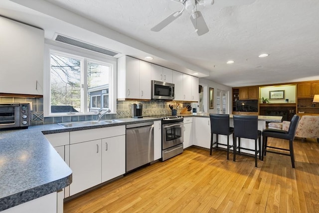 kitchen featuring light wood-style flooring, tasteful backsplash, stainless steel appliances, and a sink