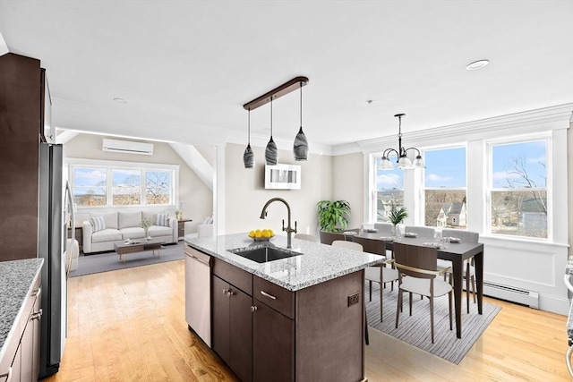 kitchen with sink, dark brown cabinetry, stainless steel appliances, a center island with sink, and a wall unit AC