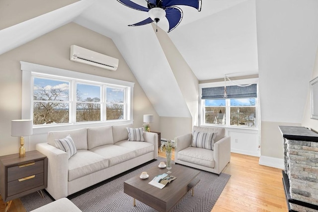 living room with vaulted ceiling, plenty of natural light, a wall mounted AC, and light wood-type flooring