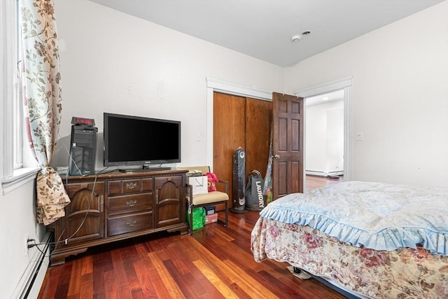 bedroom with a baseboard radiator, dark wood-type flooring, and a closet