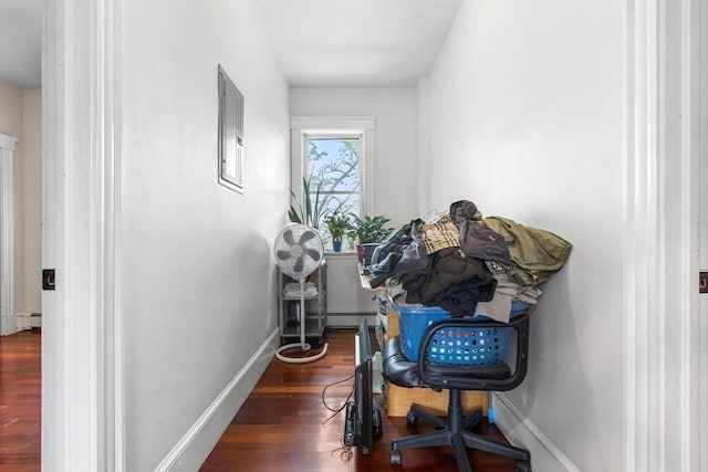 corridor featuring wood finished floors, a baseboard radiator, and baseboards