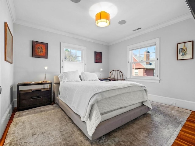 bedroom featuring crown molding, baseboards, visible vents, and wood finished floors