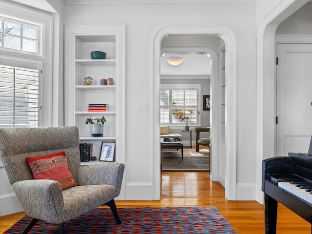 sitting room featuring built in shelves, a wealth of natural light, and light wood finished floors