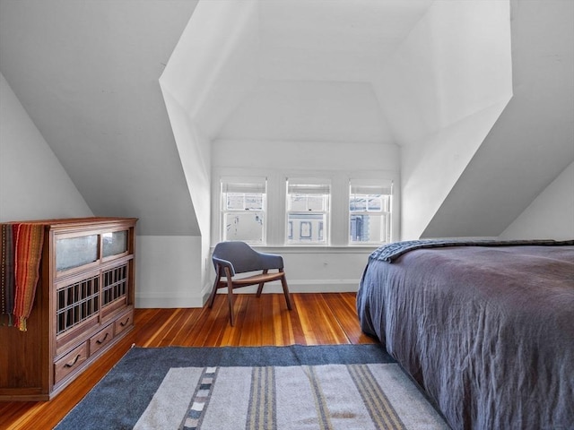 bedroom with baseboards, lofted ceiling, and wood finished floors