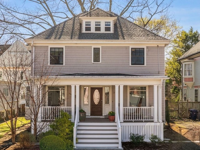 view of front of property with fence, covered porch, and a shingled roof
