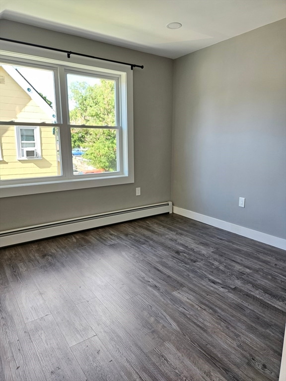 unfurnished room featuring baseboard heating and dark wood-type flooring