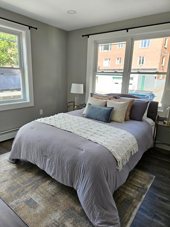 bedroom featuring dark wood-type flooring, multiple windows, and a baseboard radiator