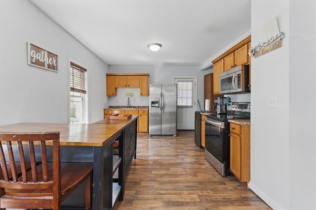 kitchen with a sink, open shelves, stainless steel appliances, and wood finished floors
