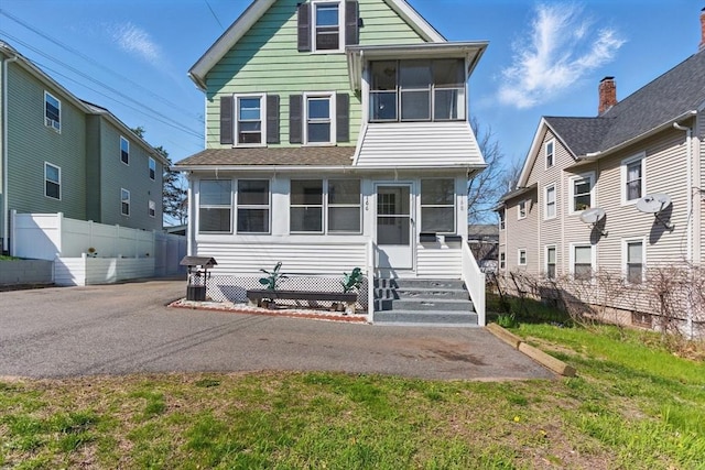 view of front facade featuring fence and a sunroom